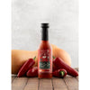 Hot sauce bottle with peppers and a pumpkin on a wooden surface