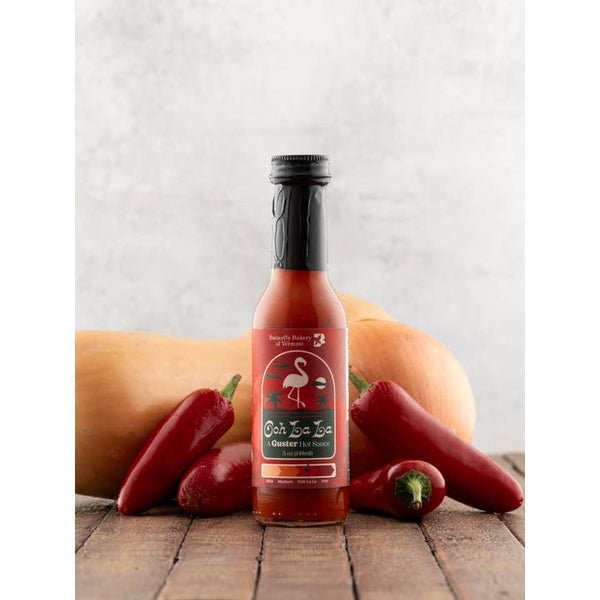 Hot sauce bottle with peppers and a pumpkin on a wooden surface
